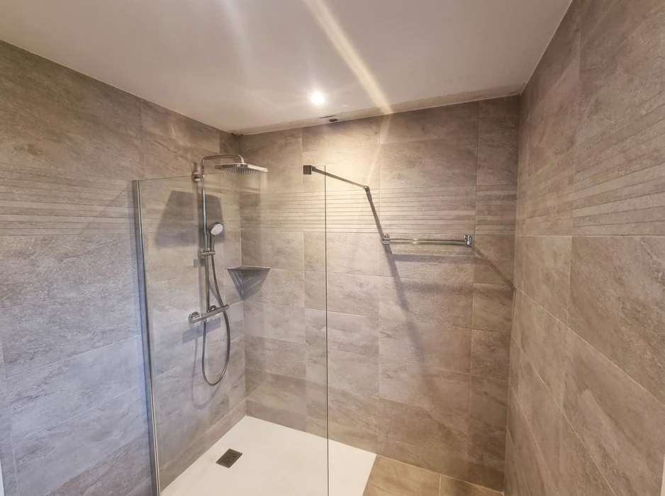 Douche à l'italienne moderne avec paroi en verre transparent fixe et barre stabilisatrice chromée