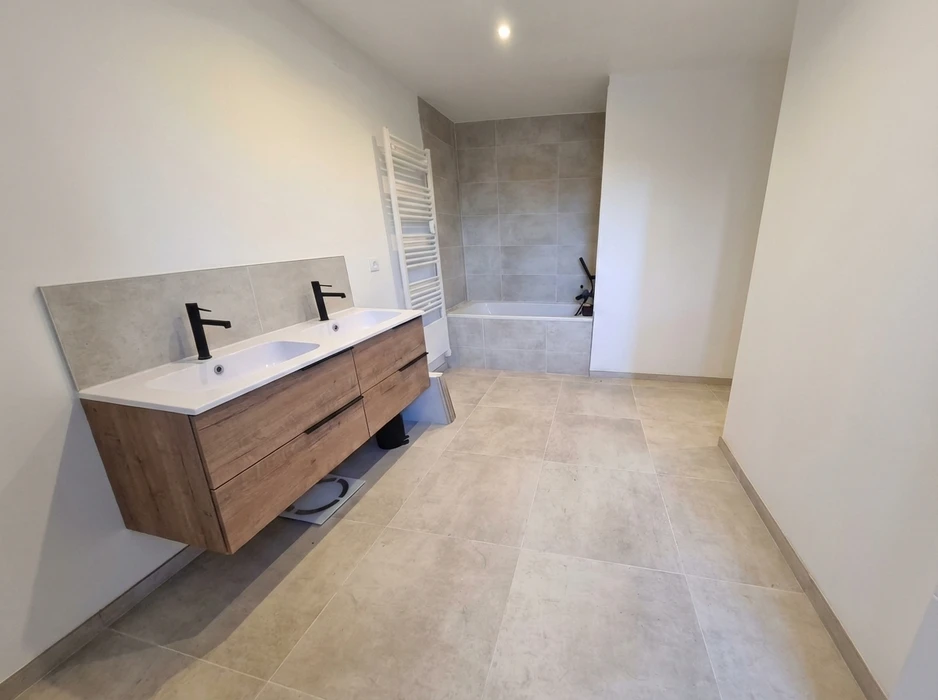 Salle de bain moderne avec double vasque encastrée sur meuble suspendu en bois imitation chêne, robinetterie noire mate, crédence en carrelage béton gris