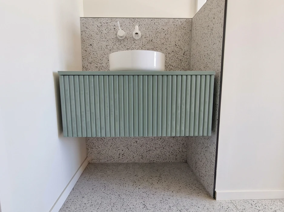 Meuble vasque suspendu en MDF laqué vert sauge, façade cannelée rainurée verticalement, plan de travail fin