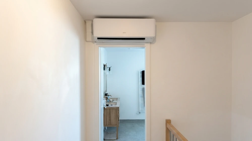 Couloir résidentiel avec climatiseur mural gainable de type split system installé au-dessus d'une porte donnant sur une salle de bain
