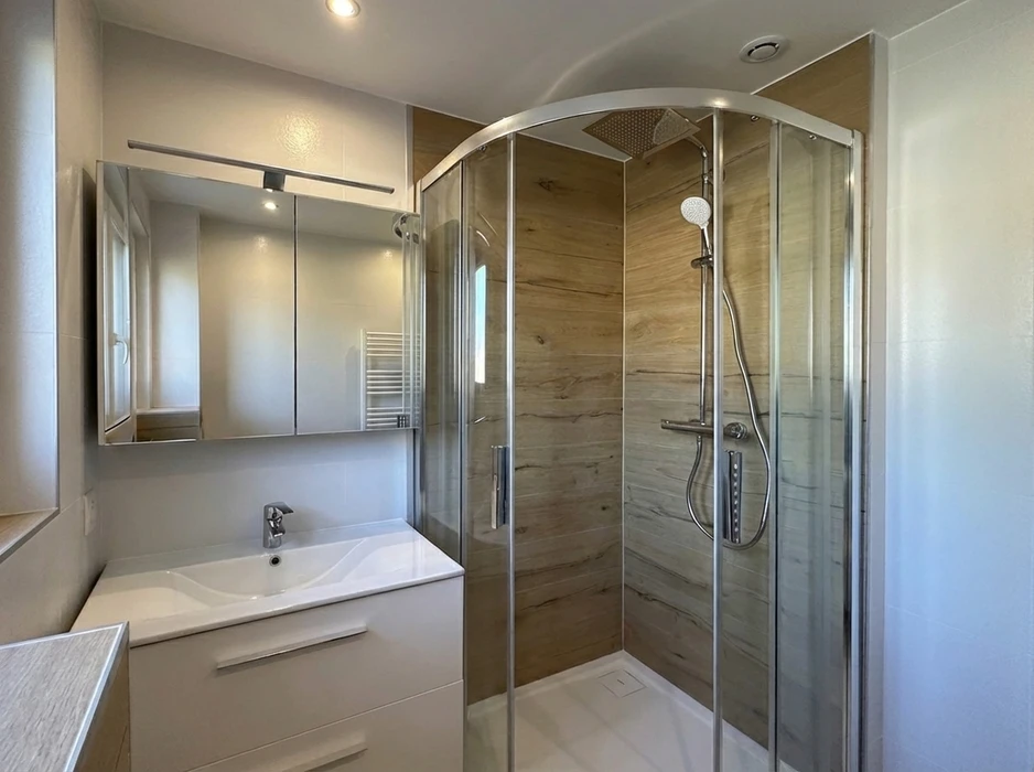Salle de bain moderne avec douche à l'italienne en angle, parois en verre transparent coulissantes à profil aluminium chromé, receveur blanc extra-plat