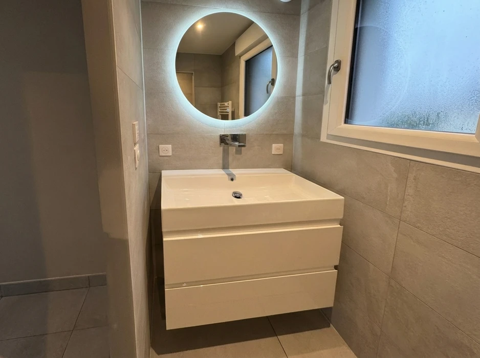 Salle de bain moderne rénovée, meuble vasque suspendu blanc laqué avec deux tiroirs, vasque à poser rectangulaire céramique blanche, robinet mural chromé encastré