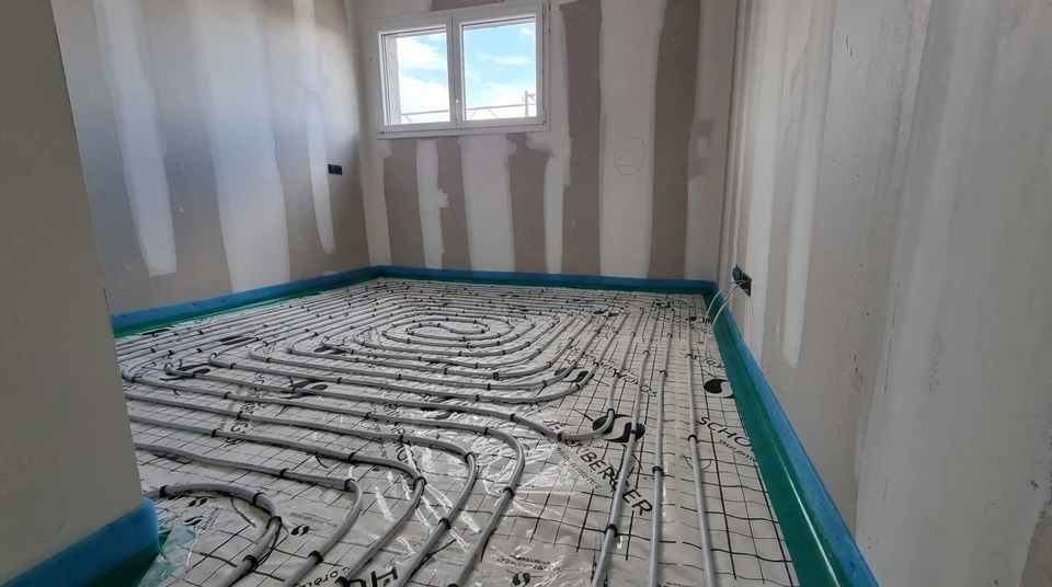Plombier en uniforme bleu travaillant dans local technique sur chauffe-eau