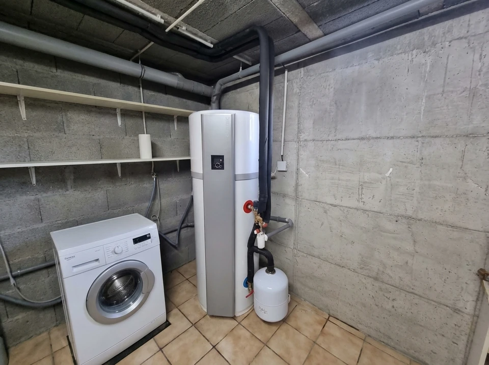 Int&eacute;rieur de salle de bain moderne avec chauffe-eau &eacute;lectrique mural blanc cylindrique install&eacute; dans angle