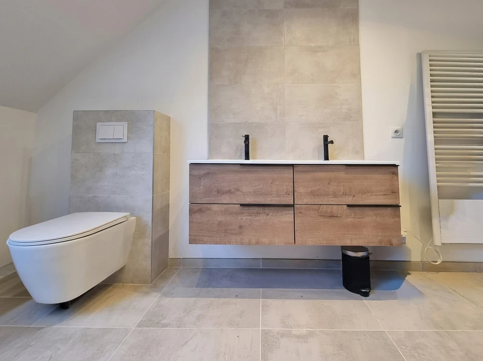 Homme en polo noir installant un équipement sanitaire dans salle de bain moderne