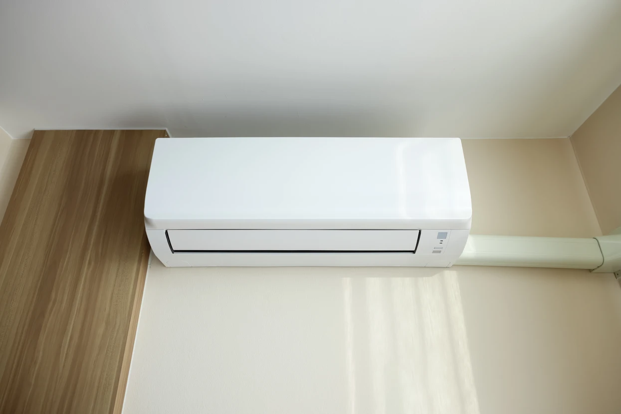 Ouvrier en combinaison bleue et casque blanc installant un radiateur chauffage central dans une pièce en rénovation